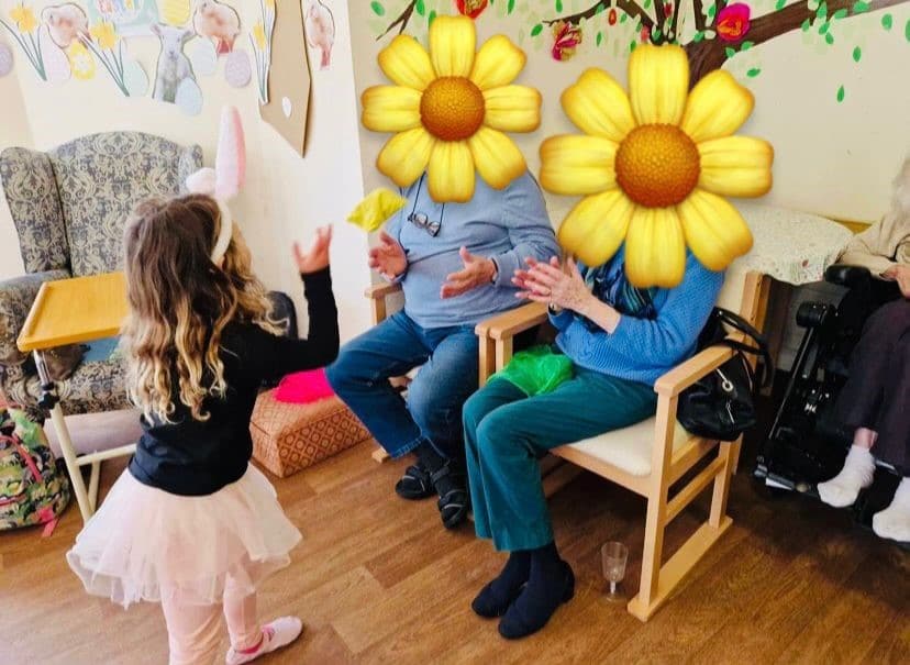 A care home resident's hand holding a toddler's hand during an intergenerational dance session